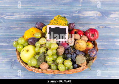 Woven basket full of autumn fruits and small chalkboard with copy space Stock Photo