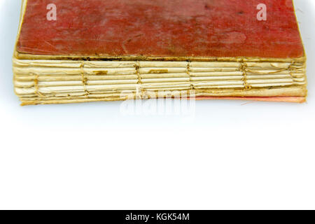 Old antique worn book with red stained cover on white. Vintage thread sewn print publication with torn out spine and visible threads. Stock Photo