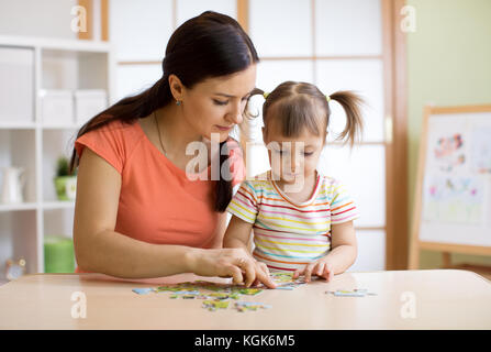 Mother and daughter playing at home. They assembling Jigsaw Puzzle. Stock Photo