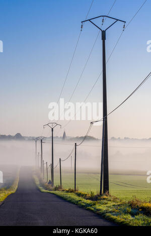 Electricity power lines alongside country road - France. Stock Photo