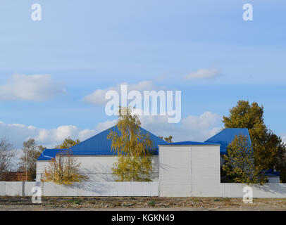 The building with siding and blue metal-plastic roof made of corrugated iron Stock Photo