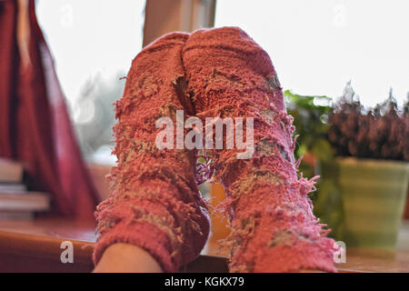 Female feet in pink woolen socks by the window, retro style tonal correction photo filter Stock Photo