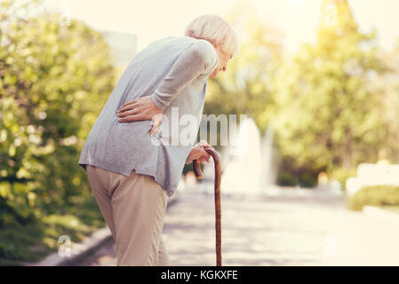 Sad aged woman leaning on the walking stick Stock Photo