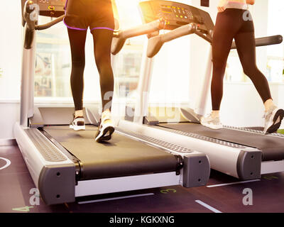 two young women running on treadmill in gym. Stock Photo