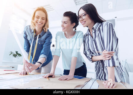 Three happy tailors working with sewing patterns Stock Photo
