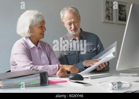Smiling business colleagues discussing over documents at desk in office Stock Photo