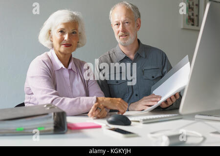 Portrait of confident business colleagues with documents at desk in office Stock Photo