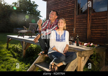 Smiling couple looking up while having wine outside farmhouse Stock Photo