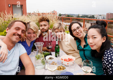 Portrait of happy friends sitting at outdoor table at patio Stock Photo