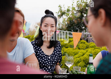 Happy young woman sitting with friends on patio Stock Photo