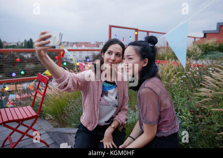 Smiling women taking selfie with smart phone on patio Stock Photo