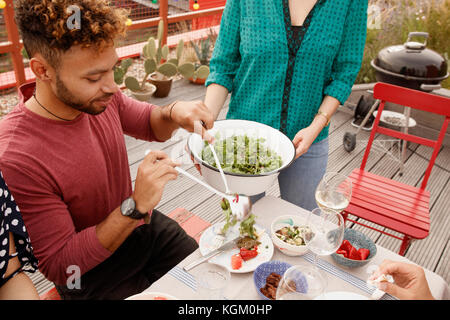 High angle view of man serving salad in plate at patio Stock Photo