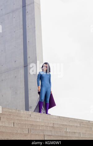 Low angle view of confident female superhero standing on steps against clear sky Stock Photo