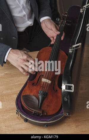 Midsection of man keeping violin in case at table Stock Photo