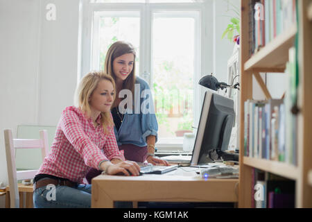 Beautiful young female friends using computer at home Stock Photo