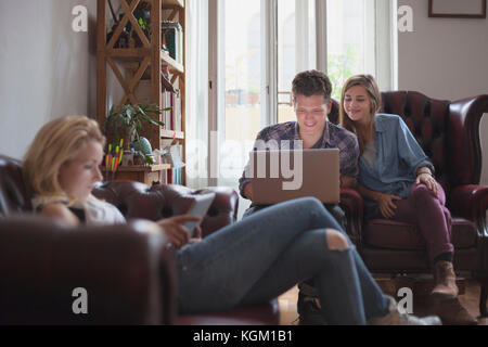 Woman with digital tablet while friends using laptop at home Stock Photo