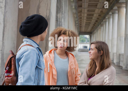 Young multi-ethnic friends talking while standing in corridor, Berlin, Germany Stock Photo