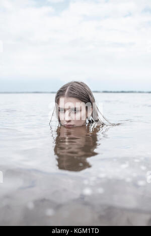 Thoughtful young woman swimming in lake against sky Stock Photo