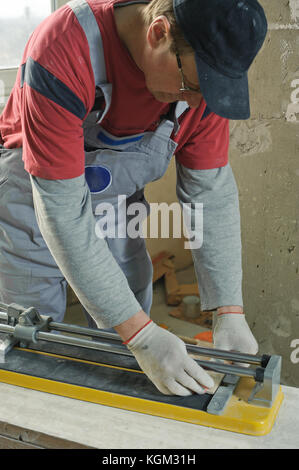 Laying Ceramic Tiles. Tiler cuts tile  manual cutter Stock Photo