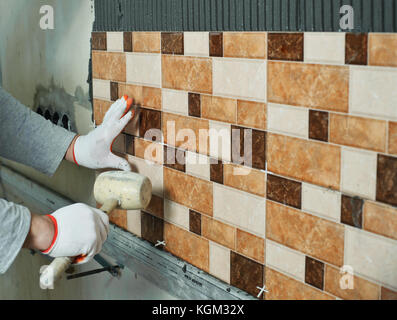 Laying Ceramic Tiles. Tiler knocking on the tiles with a rubber mallet Stock Photo