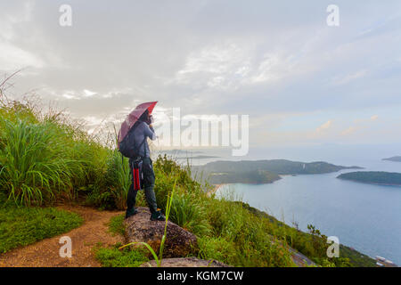 a lady drinking coffee on the highest viewpoint name Pha Hin Dum. on Pha Hin Dum viewpoint can see around Phuket island. Niharn beach wind turbine Pho Stock Photo