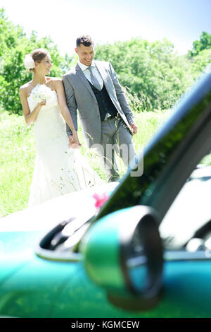 Bride and groom walking towards convertible car Stock Photo