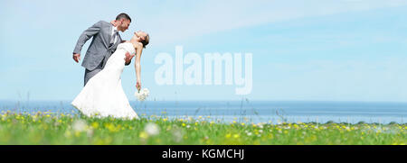 Bride and groom standing together in front of the sea Stock Photo