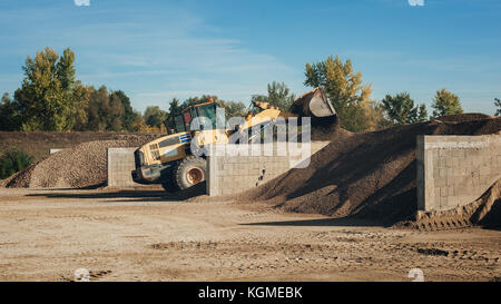 Bagger scooping gravel at construction aggregate dumps at concrete production plant Stock Photo
