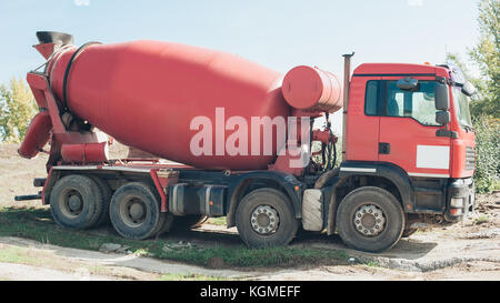 Red concrete mixer vehicle on the construction site. Construction aggregate dumps Stock Photo