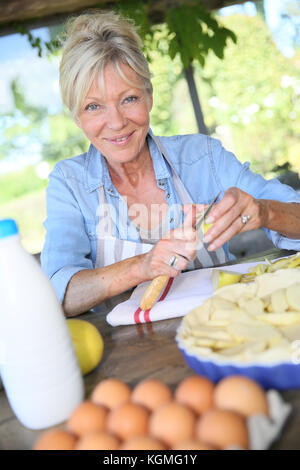 Senior woman cutting apples for pastry receipe Stock Photo