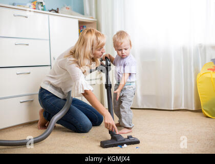 Cleaning up the room together - mother and her kid son with vacuum cleaner Stock Photo