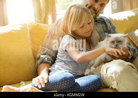 Daddy with little girl petting cat sitting on sofa Stock Photo