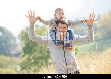 Daddy holding son on his shoulders out in the countryside Stock Photo