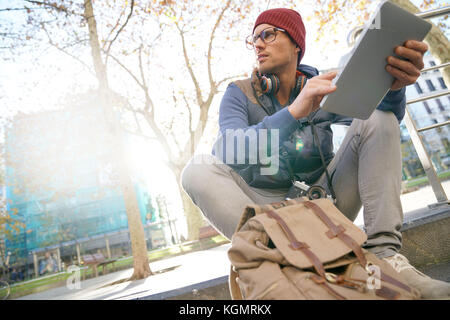 Hipster guy in the street websurfing on tablet