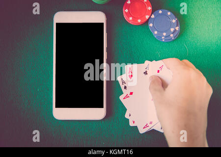 blank screen smartphone, chips and cards over poker table. Gambling concept. Stock Photo