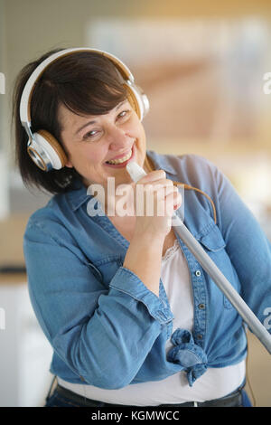 Cheerful overweigth woman having fun sweeping the floor Stock Photo