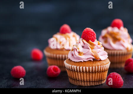 Delicious raspberry and caramel cupcakes on dark background Stock Photo