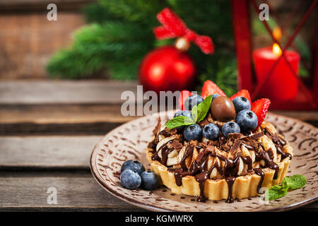 Banoffee chocolate pie decorated with chocolate, fresh blueberry and strawberry, holiday christmas background Stock Photo