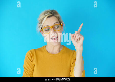 Portrait of blond woman with yellow eyeglasses pointing at message Stock Photo