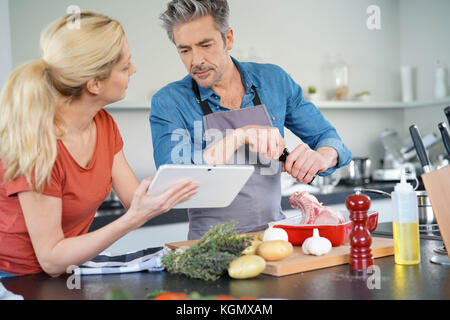 Couple in home kitchen using electronic tablet Stock Photo