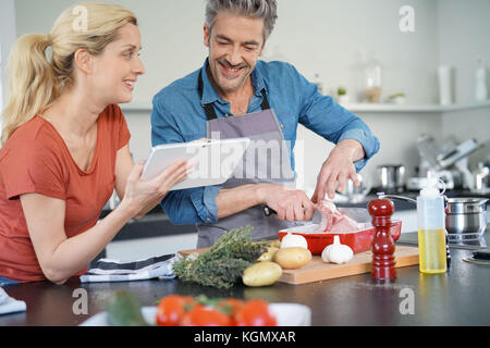 Couple in home kitchen using electronic tablet Stock Photo