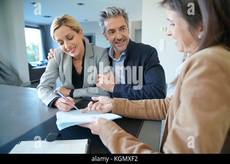 Clients signing sales agreement with real-estate agent Stock Photo
