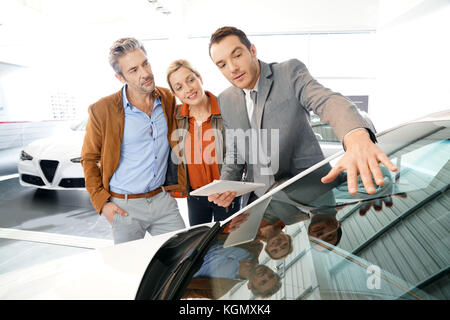Car seller with couple in car dealership Stock Photo