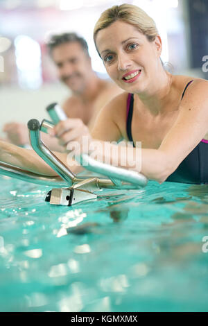 Couple in swimming-pool doing aquabike exercises Stock Photo