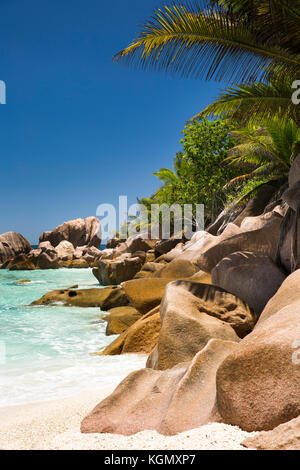 The Seychelles, La Digue, Petit Anse, beach, eroded granite rock formation in sea Stock Photo