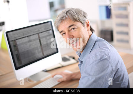 Businessman in office working on deskptop computer Stock Photo