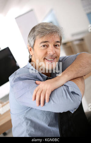 Smiiling mature man relaxing in office chair Stock Photo