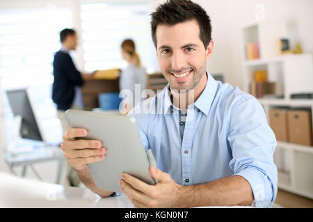 Smiling man in office working on digital tablet Stock Photo