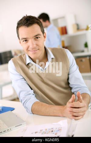 Smiling man sitting at desk in office Stock Photo