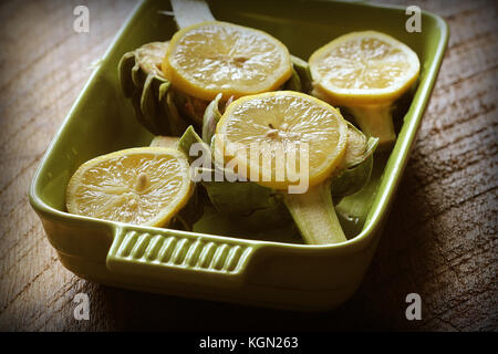 Artichokes recipe with garlic and lemon on pan . Ready for cooking Stock Photo